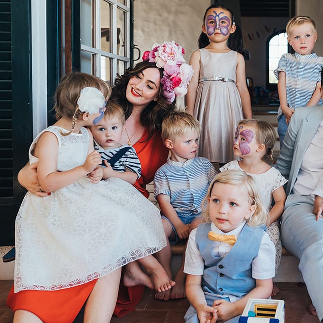 Brides pose for photos on their wedding day with children 