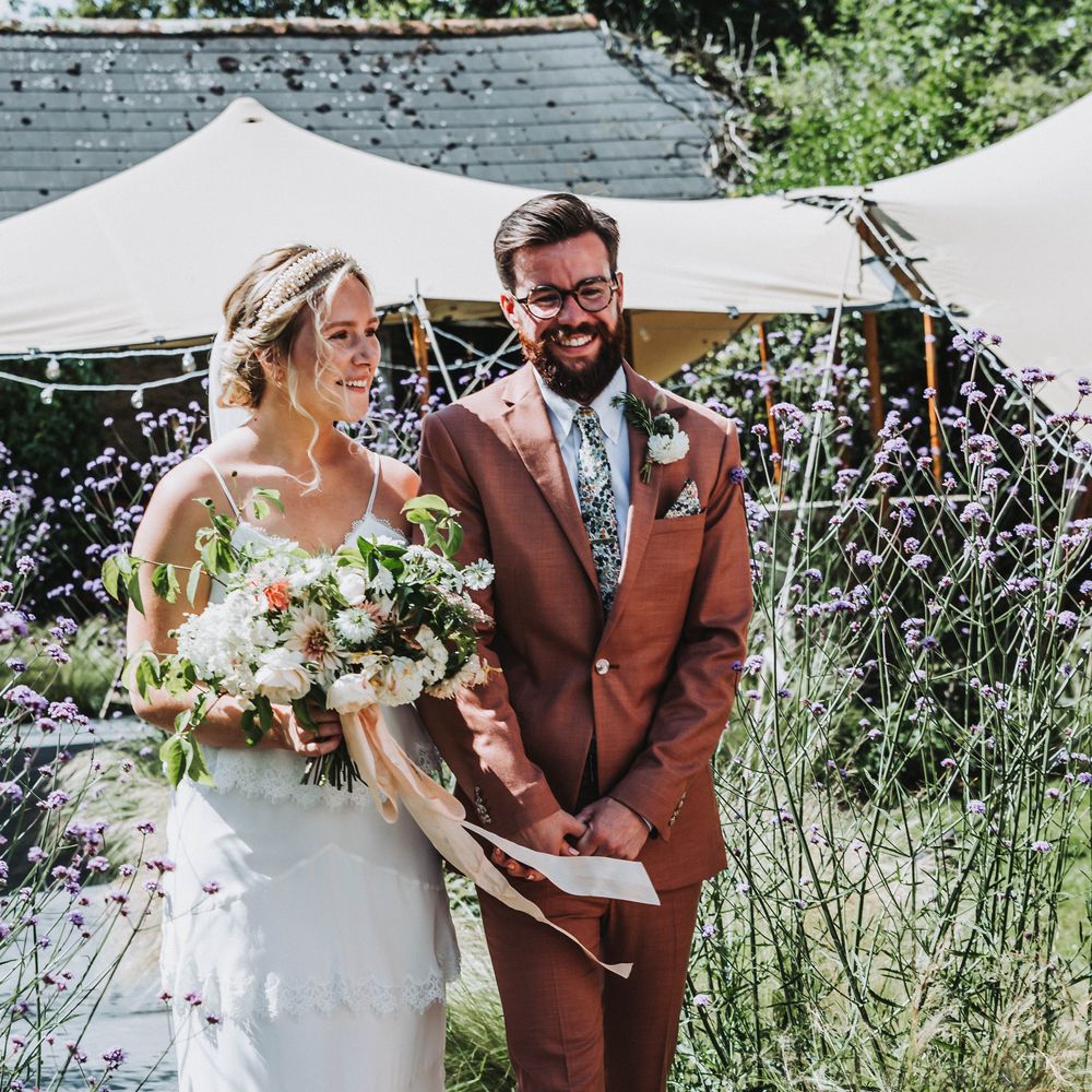Bride & groom walk down the aisle after their wedding ceremony as wedding guests throw dried confetti 