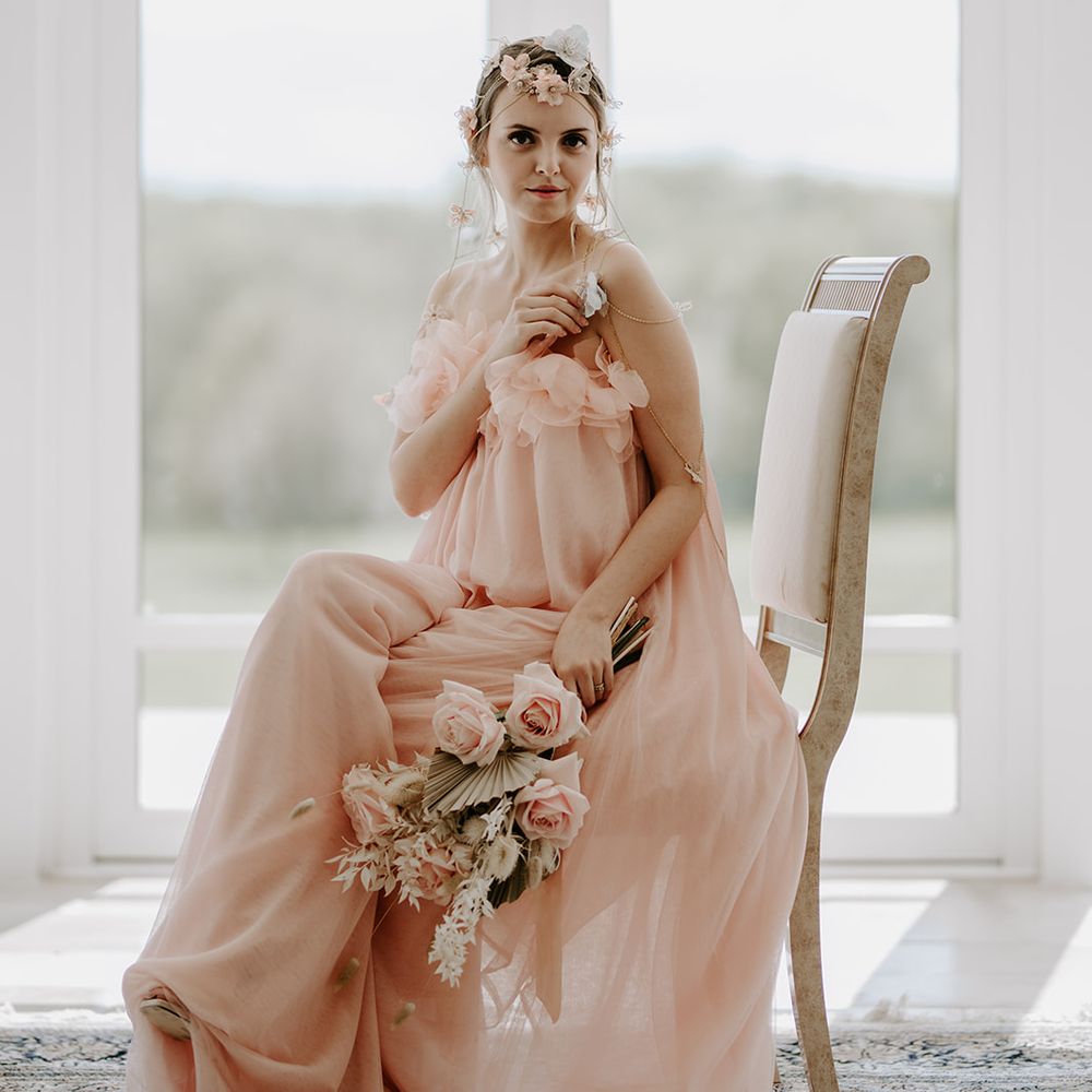 Boho bride in a strapless blush pink wedding dress with appliqué flowers and a chain headdress
