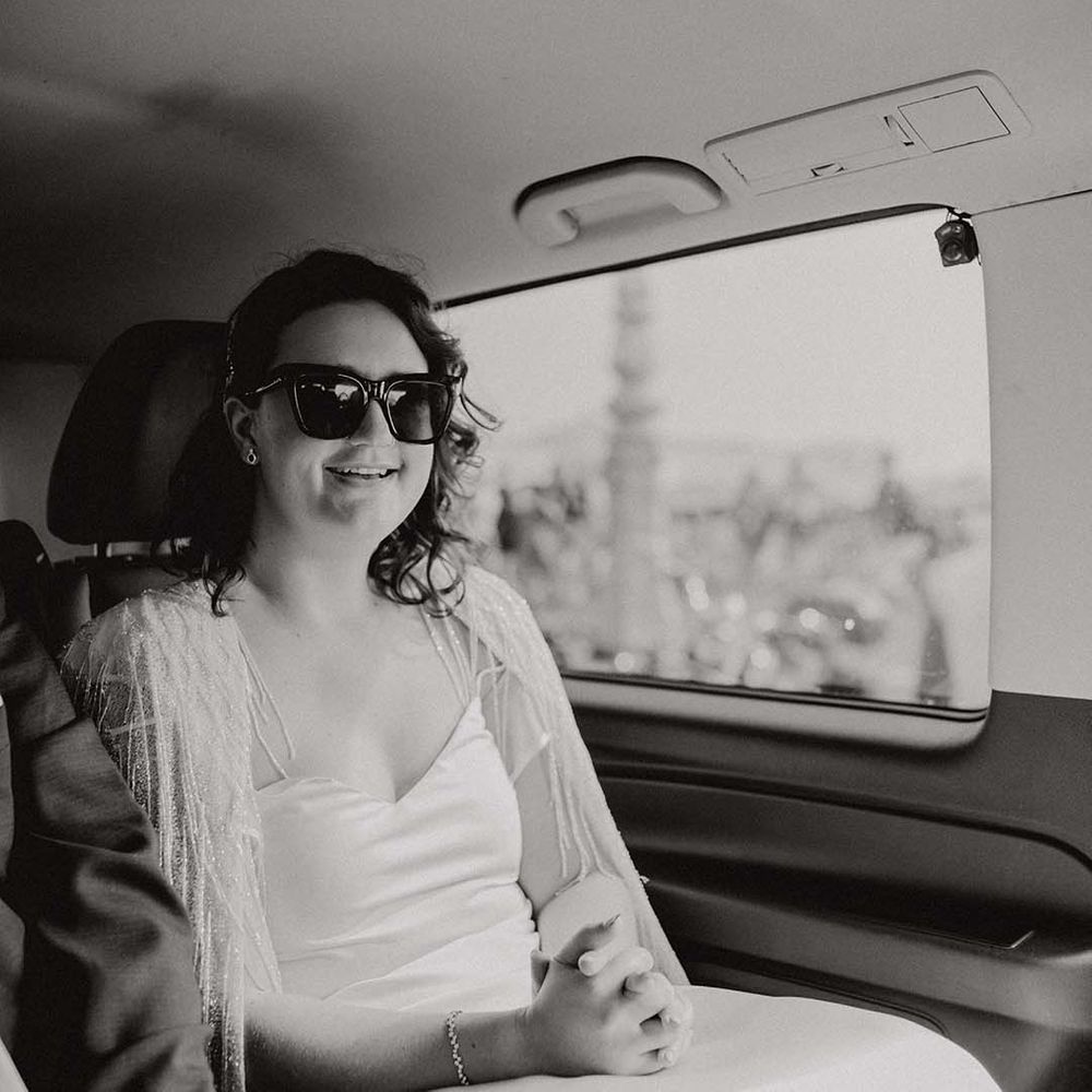 Bride wears sunglasses on her wedding day whilst sat in car 