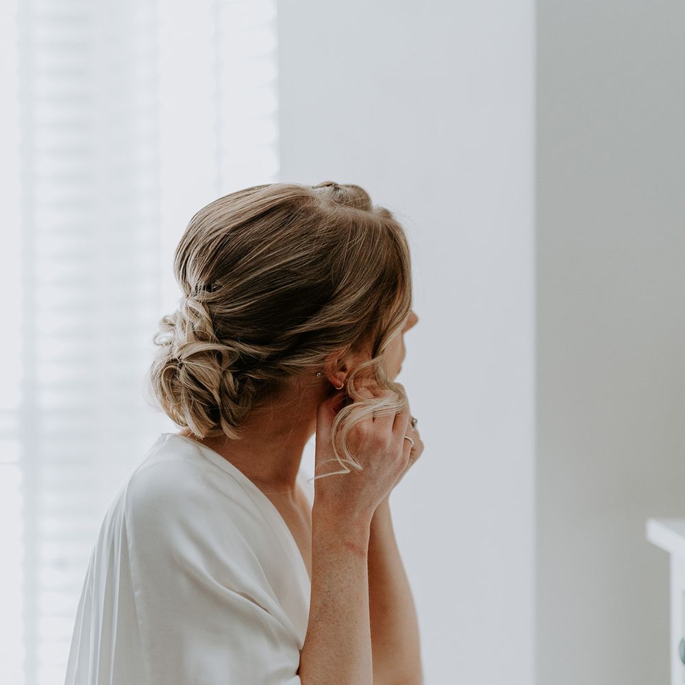 Bride puts in her earrings on the morning of her wedding