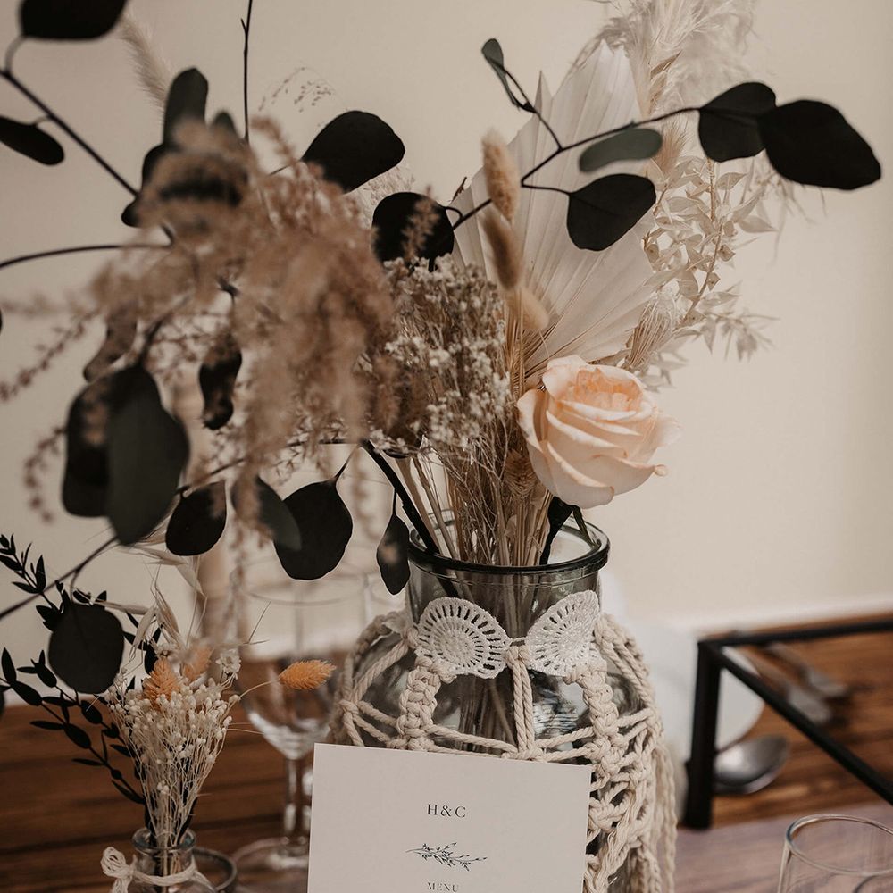 Wedding stationery in front of vase covered in macrame 
