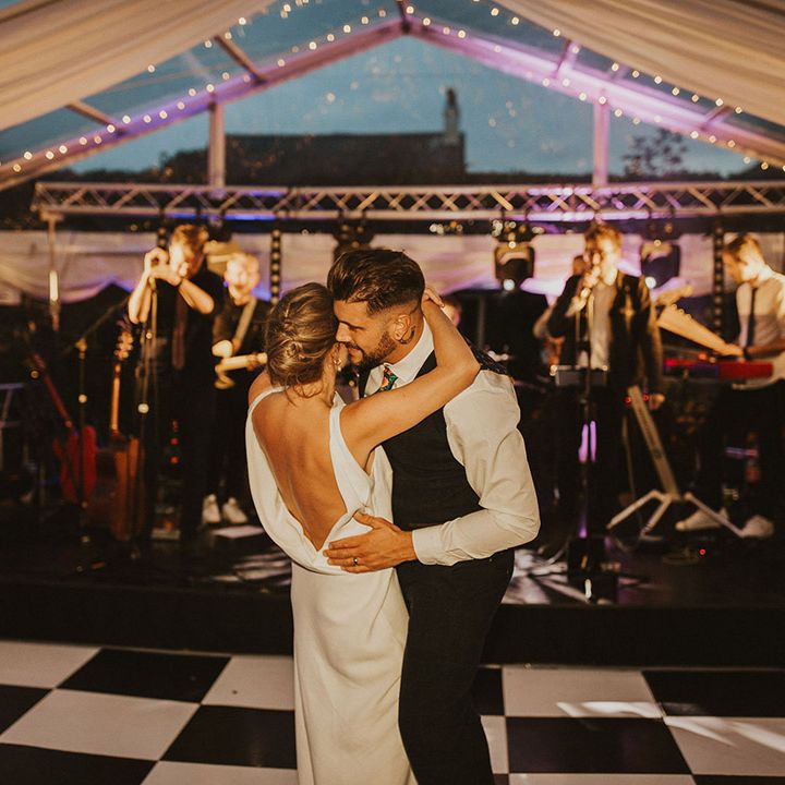 Bride and groom first dance in a clear marquee with bride in a low back Charlie Brear wedding dress