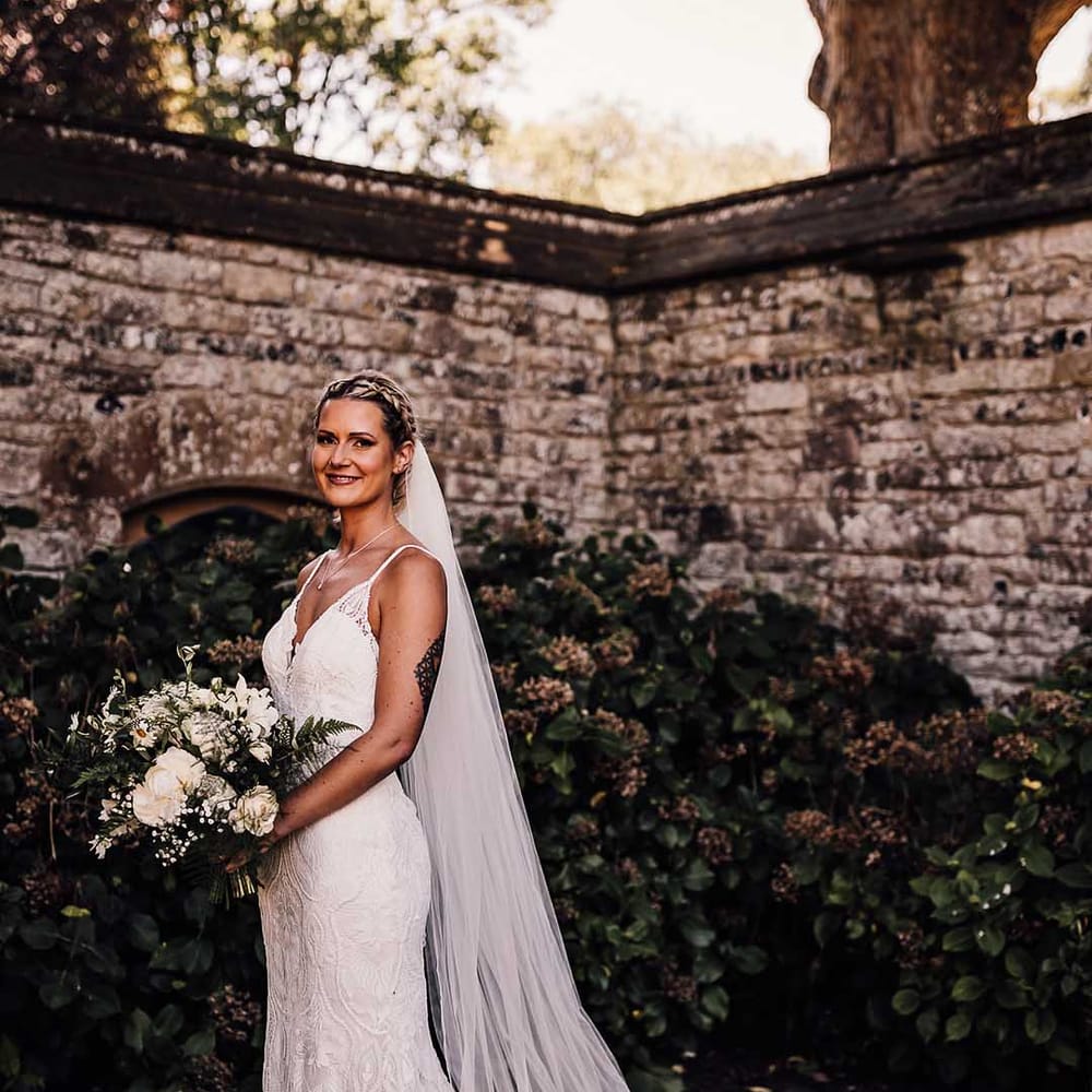 Bride in lace wedding dress with train and veil for outdoor wedding at Athelhampton House