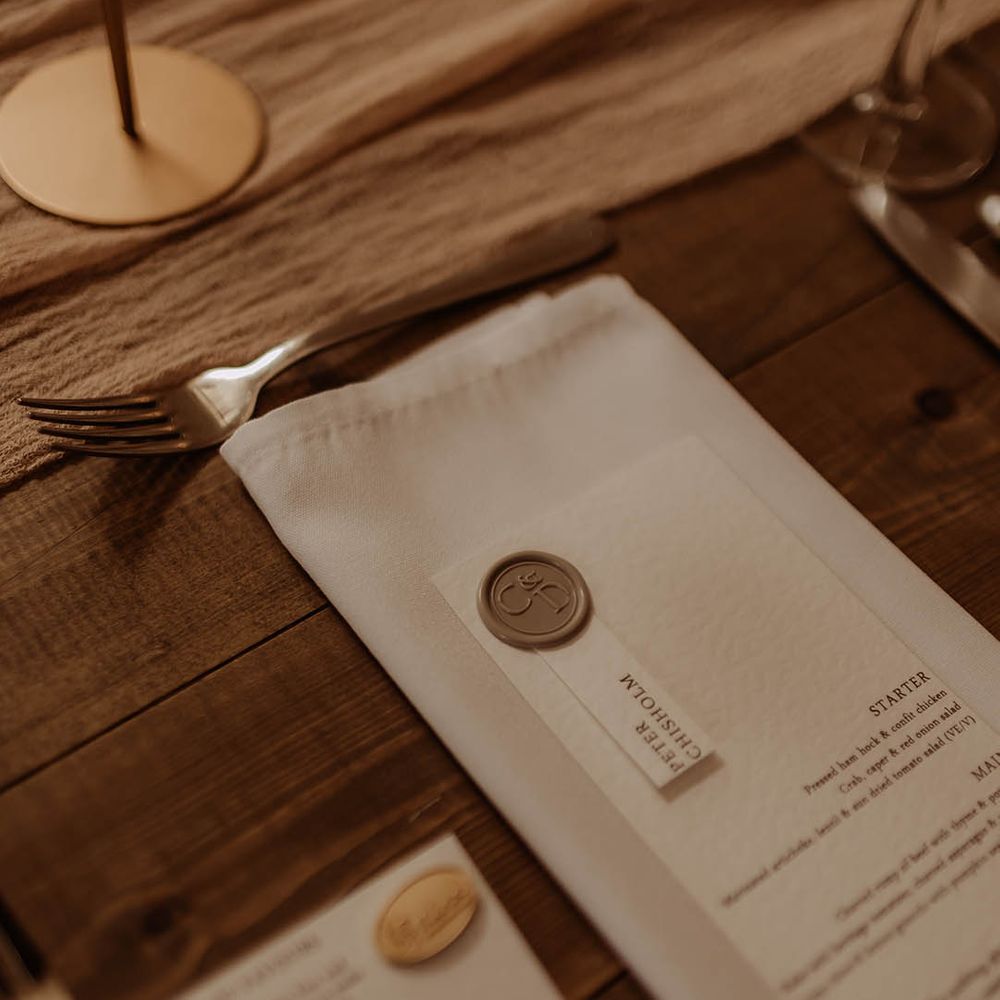White napkin with white wedding menu with gold wax seal decoration for boho luxe wedding 