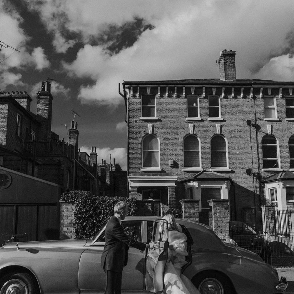 Bride getting into a vintage wedding car at modern stylish London wedding 