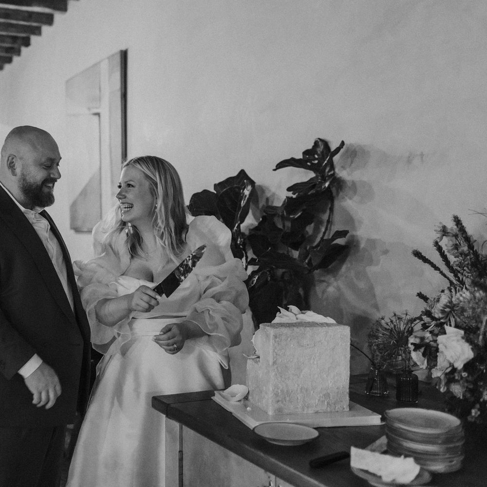 Bride and groom cutting their square wedding cake at evening reception 