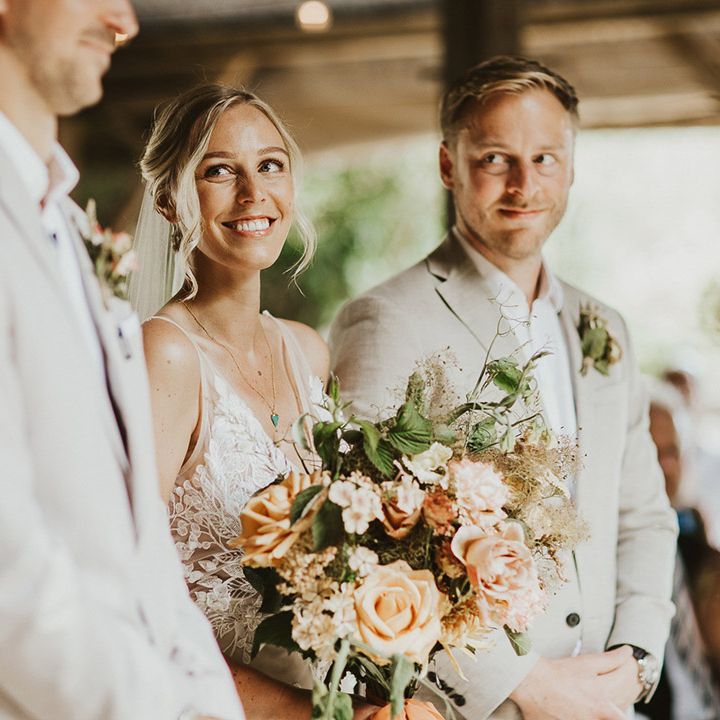 Bride stands at the altar holding her pastel wedding bouquet looking lovingly up at the groom for the ceremony 