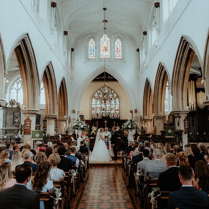 Bride and groom stand holding hands for their church wedding ceremony 