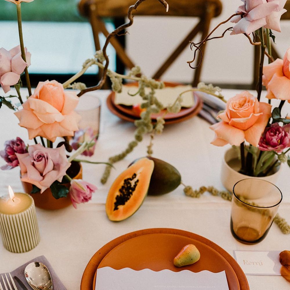 Colourful wedding tablescape with terracotta plates, lavender napkins, fru8it decor and pops of colour with the flowers and candles 