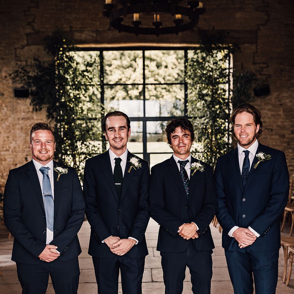 Groom with the groomsmen in navy blue suits and different colour and style ties 