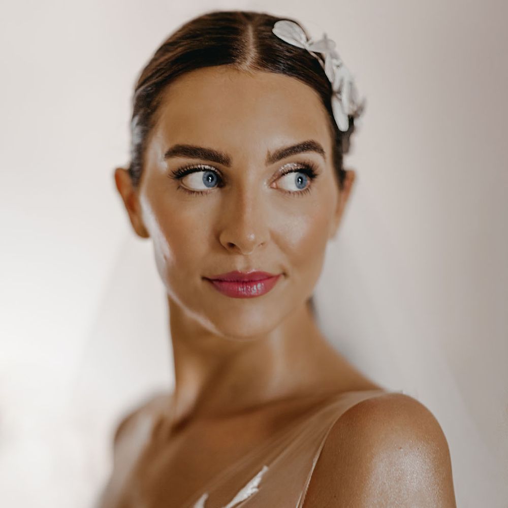 Bride with a pink lip and glittery eyeshadow smiling for her big day 