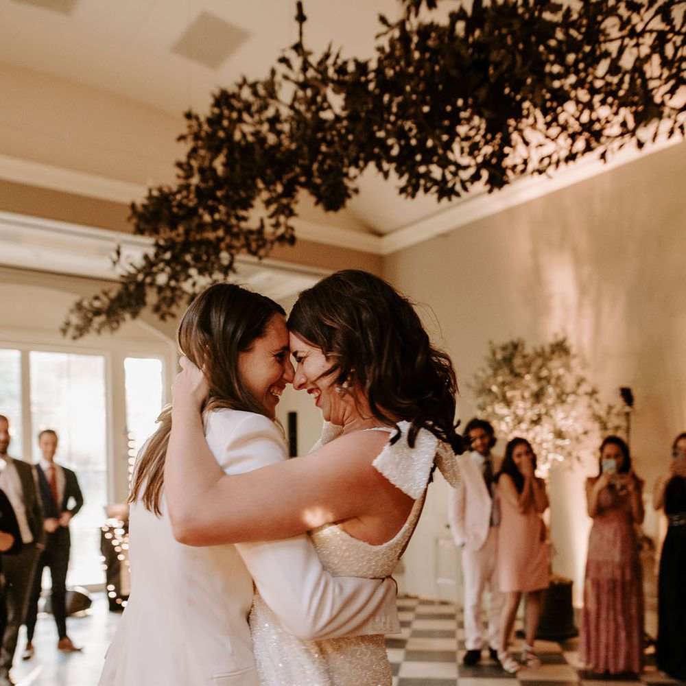 Bride in a halter neck white sparkly dress sharing the first dance with the bride in a white suit 