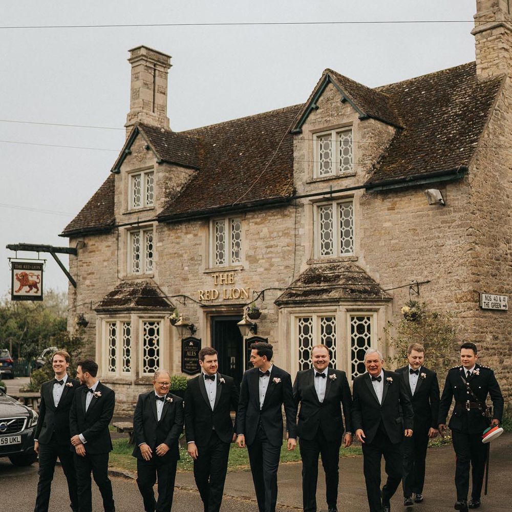 Groom and the groomsmen in matching black tie walk from the pub to the wedding 