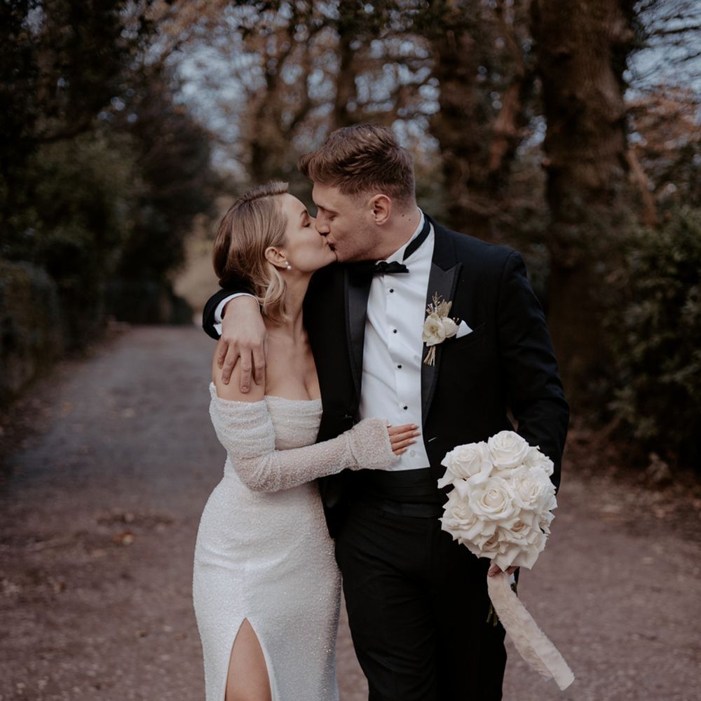 Groom in black tie kissing the bride in an off the shoulder sparkly wedding dress 