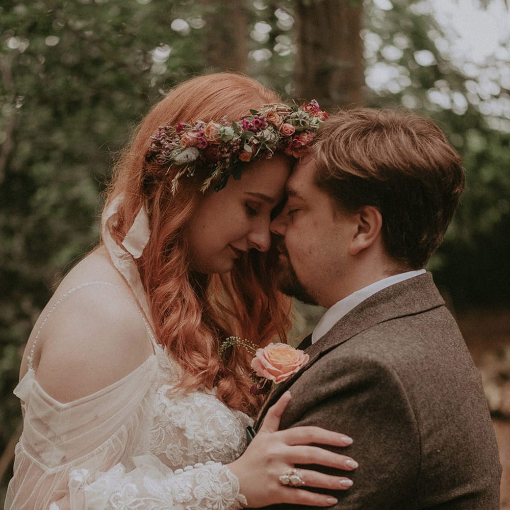 Lila's Wood wedding with the bride wearing a floral lace wedding dress and pink flower crown with the groom in tweed suit 
