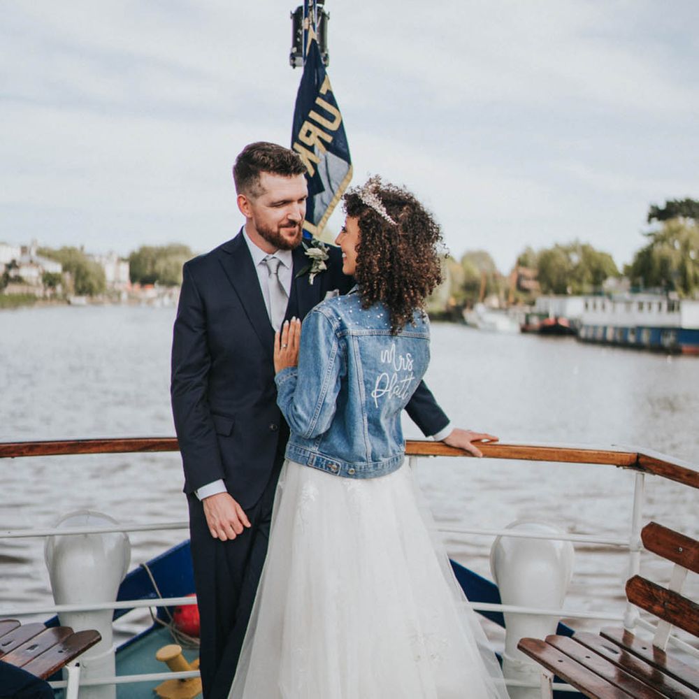 Bride in tulle princess wedding dress with sparkly tiara in personalised pearl denim cover-up with the groom on boat ride 