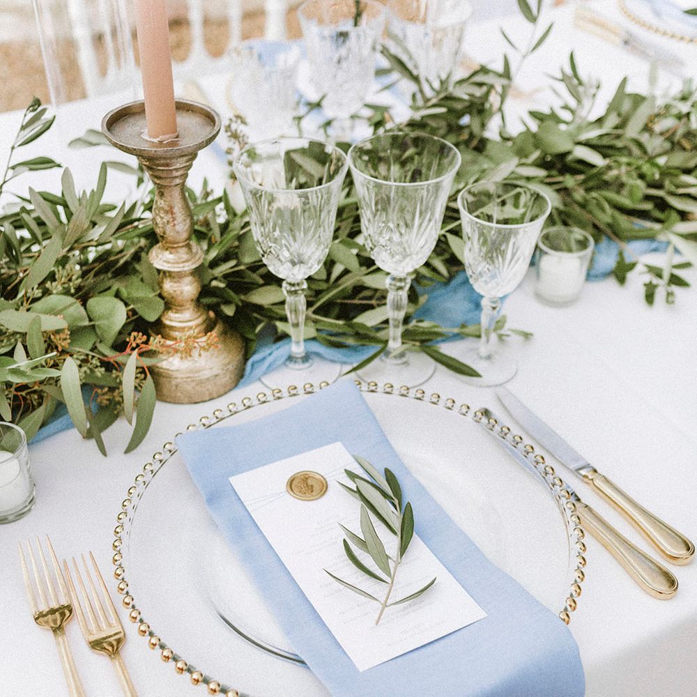 Gold charger plates with gold cutlery and gold rimmed glassware with blue napkin 