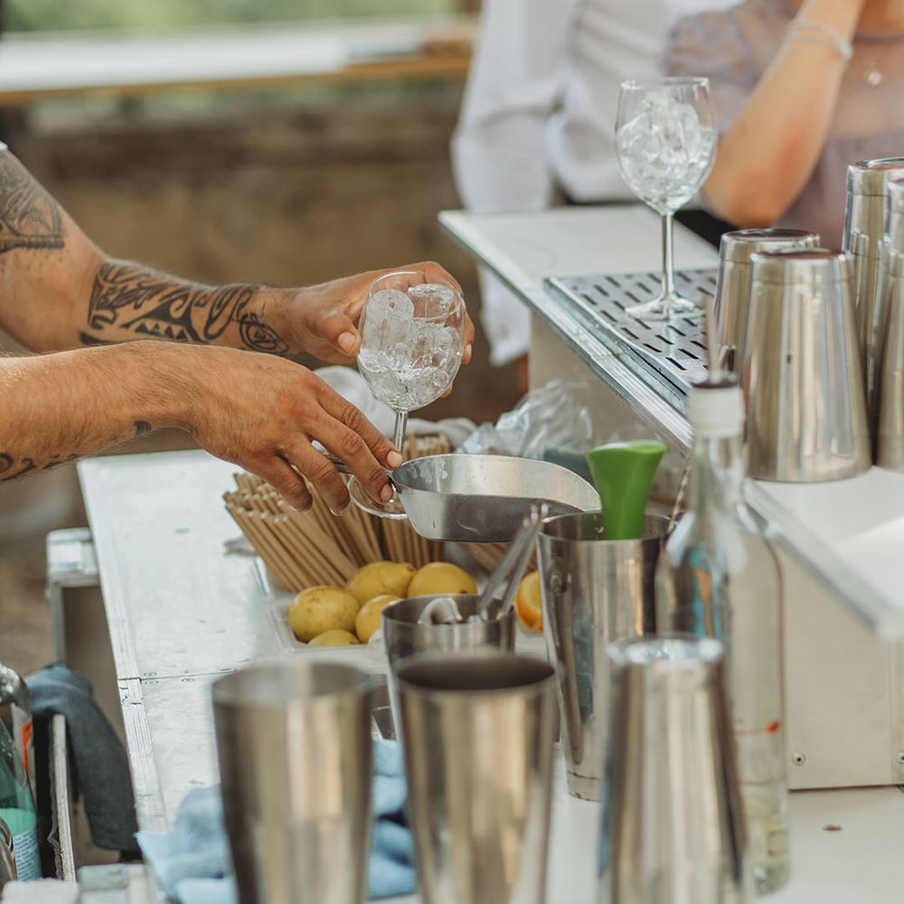 Mixologist makes wedding cocktails at outdoor cocktail cart bar 