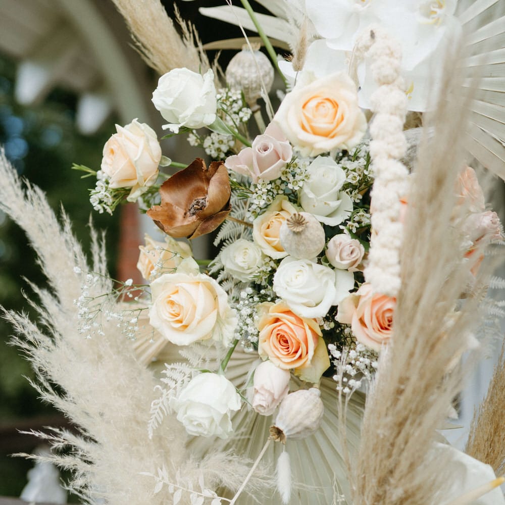 Flower archway detail of dried palms, pampas grass, roses, dried poppy heads and white anthuriums