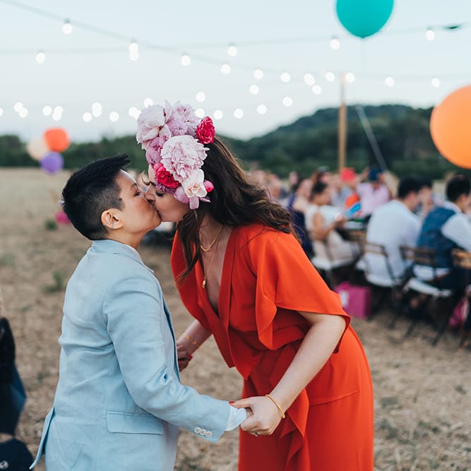 Brides kiss outdoors during wedding reception on their wedding day