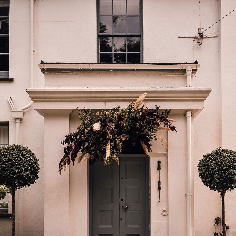 Exterior of White House in Cornwall decorated for wedding reception with floral cloud above door