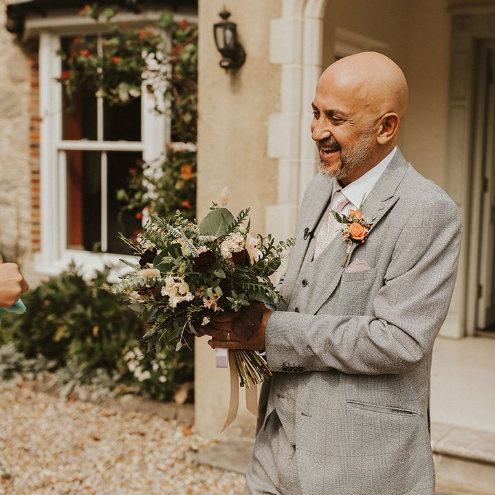 Wedding guest in grey suit with orange flower buttonhole 