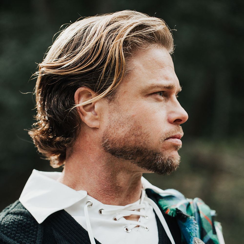 Bearded groom with long wavy hair in highland attire with aran tank top