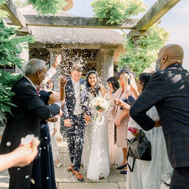 Bride & groom walk through wedding guests as they throw confetti around them