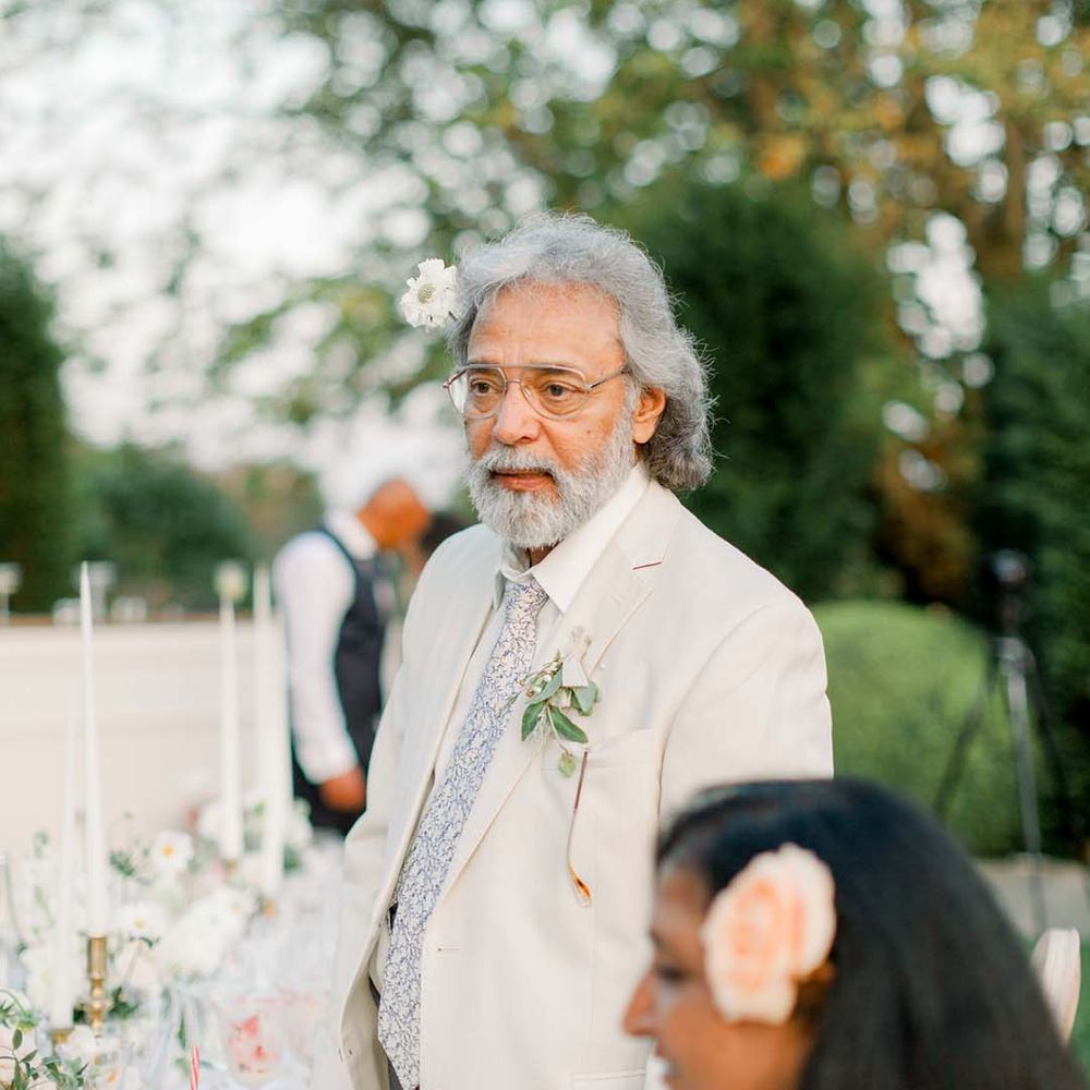 Wedding guest wears white suit outdoors during wedding reception