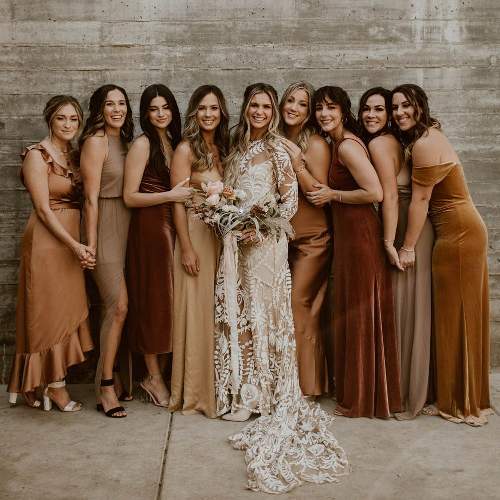 Bride stands with her bridesmaids who wear different styled gowns 