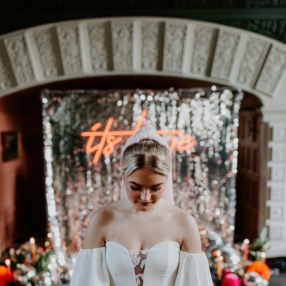 Bride in a strapless wedding dress with plunging lace neckline holding a red and orange tulip bouquet 