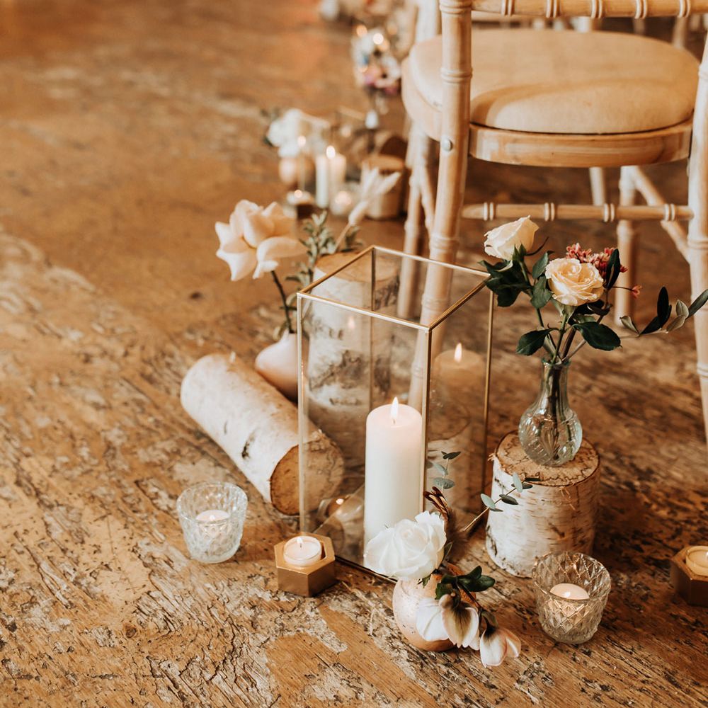 Pillar candles, pink roses and log aisle decor for wedding ceremony