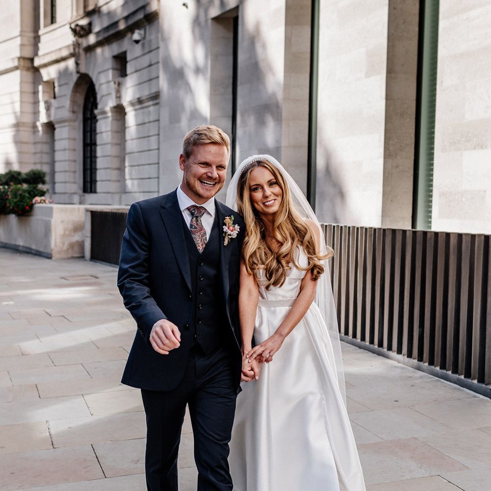 Bride and groom portrait with groom in a navy blue wool suit and floral tie and the bride in a classic princess wedding dress with long veil 