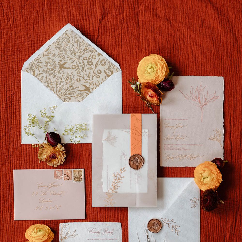 Flat lay of a wedding stationery suite including and invitation, RSVP card, envelopes and vellum wrap with wax seal 