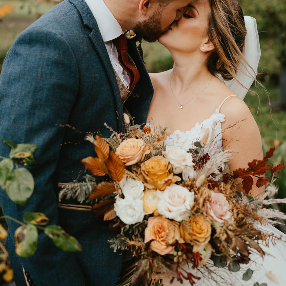 Bride and groom share a kiss with bride wearing a sequinned top and tulle skirt wedding dress and groom in a blue suit 