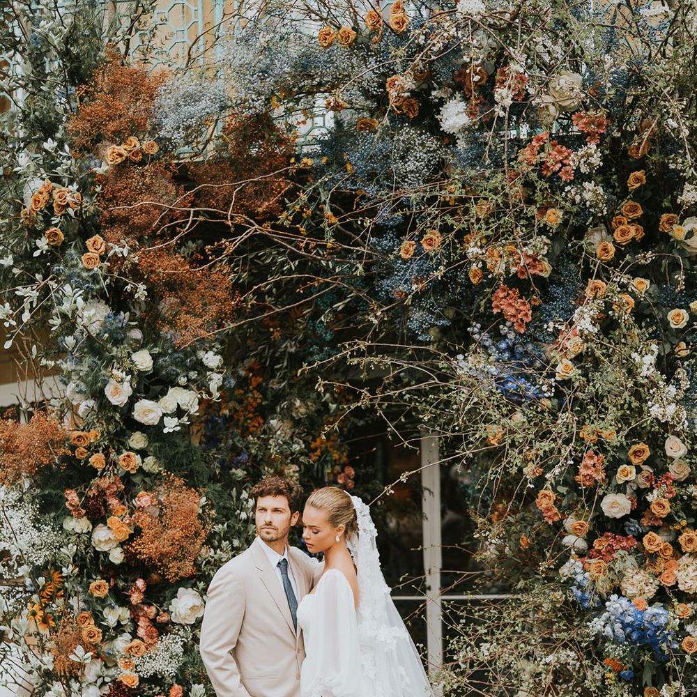 Orange, white and blue large wedding flower arch altar decoration for outdoor ceremony with bride and groom 