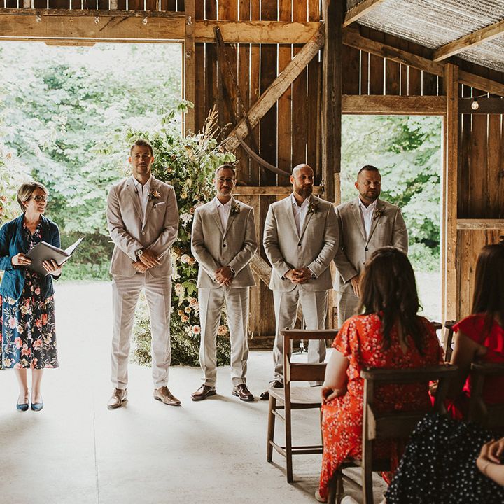 Groomsmen in light wedding suits standing next to the groom as he waits patiently for the bride 