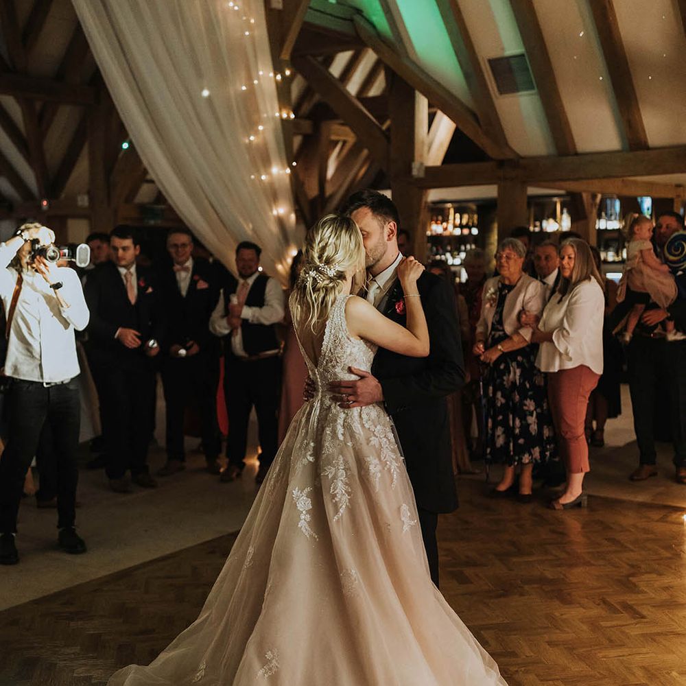 Bride and groom share a kiss while they're having their first dance together at their barn wedding venue 