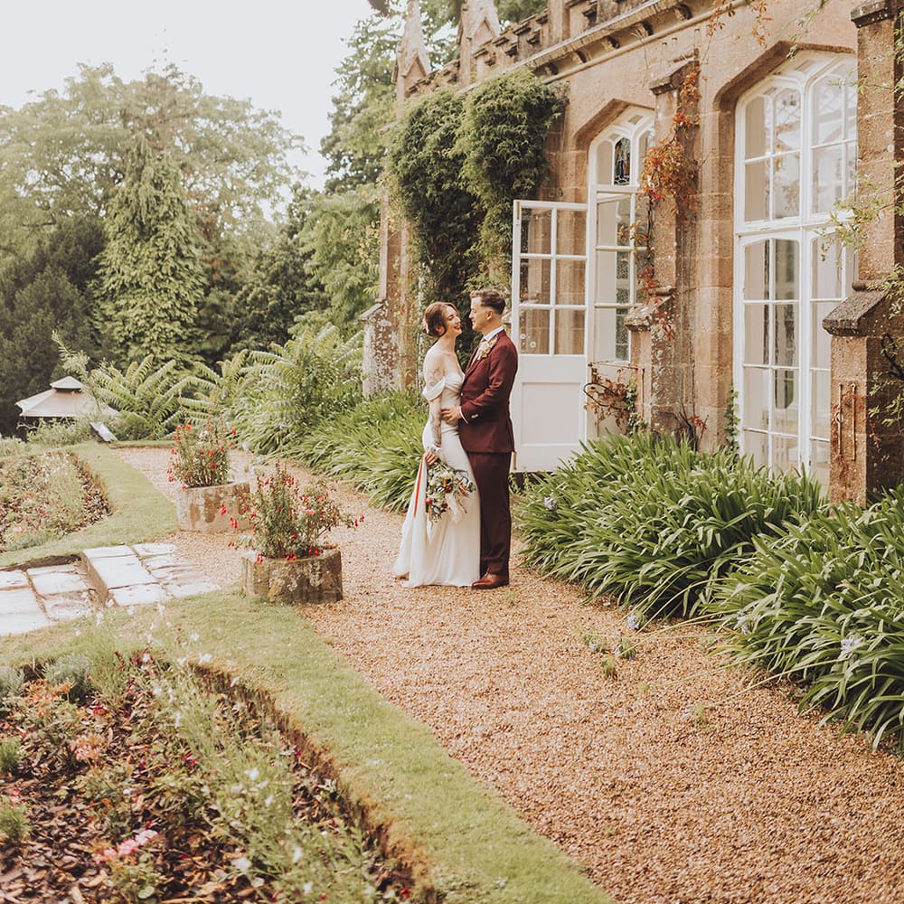 Bride & groom stand outdoors for couples portraits at St Audries Park wedding venue 