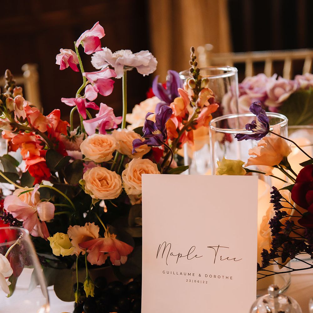 Vibrant flower wedding centrepieces with lemon decor and minimal table name sign 