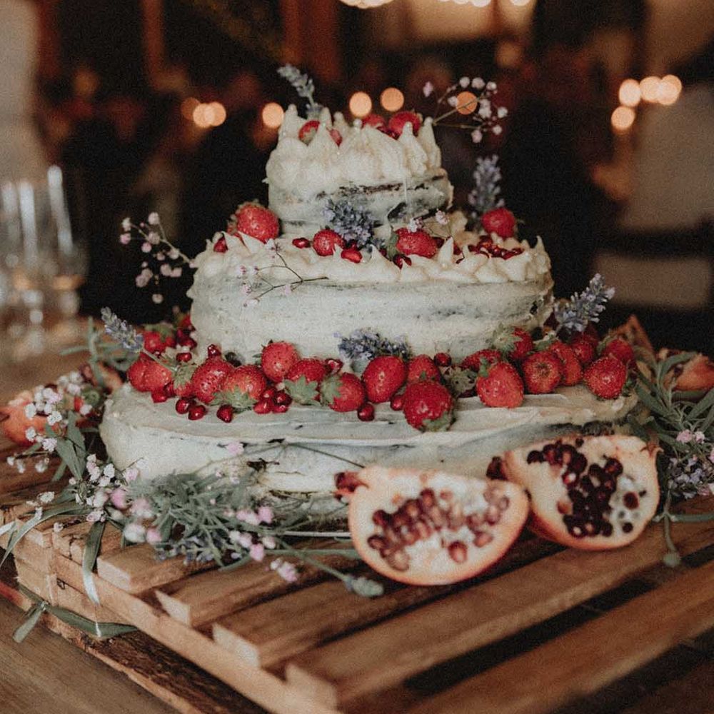 Homemade wedding cake complete with strawberries, pomegranate and white frosting 