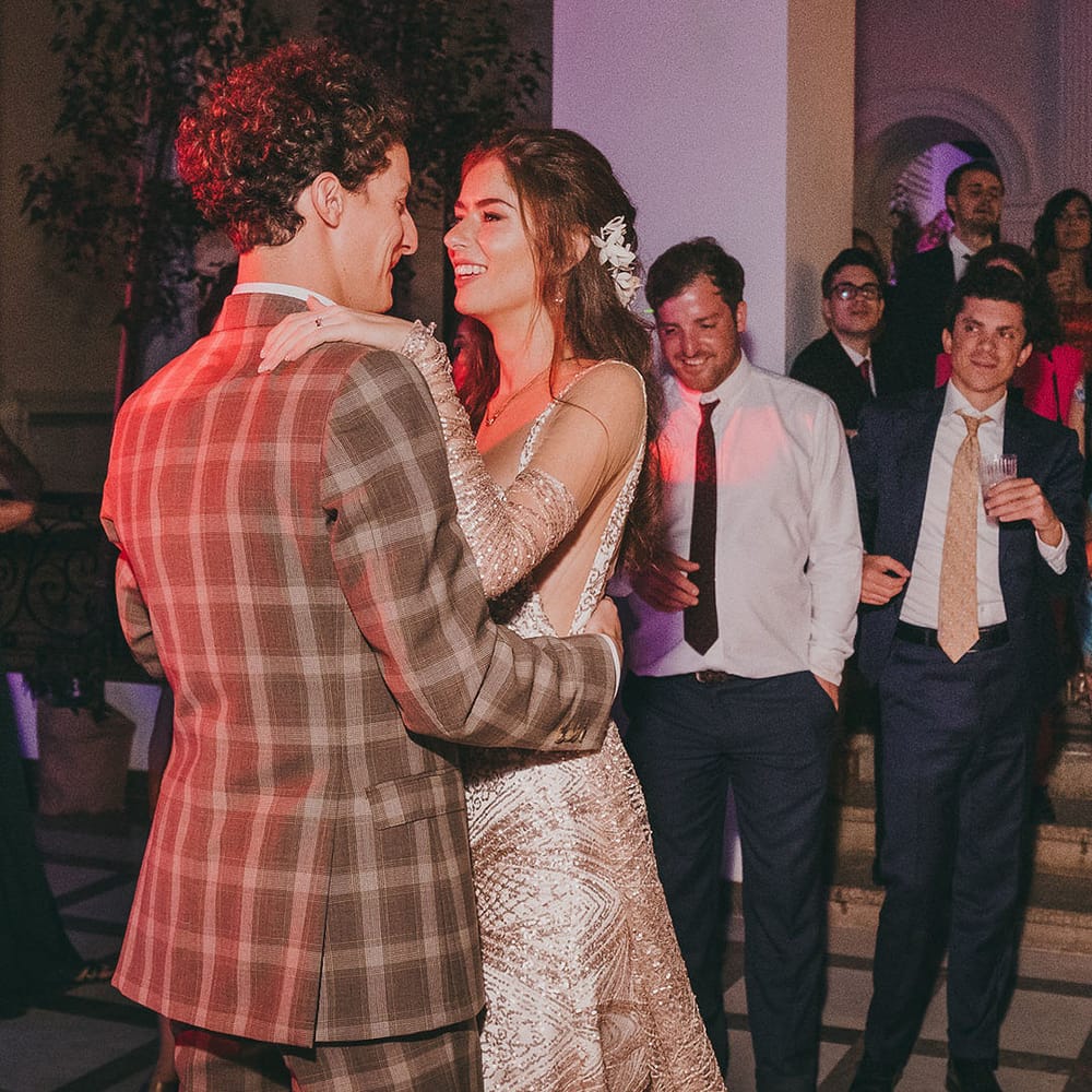 Bride and groom first dance with groom in a check suit and bride in a gold dress