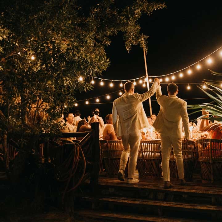 Grooms in complimenting white double breasted grooms suits walking into wedding reception at destination beach wedding in Mexico 