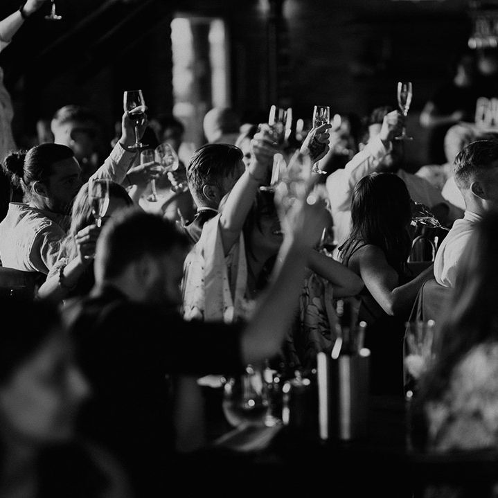 Wedding guests raise their glasses in a toast for the new happy couple 