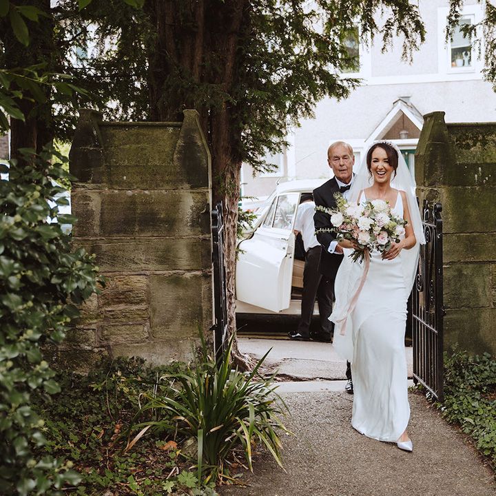 The bride in a satin slip wedding dress walks to the church for a Catholic wedding ceremony 