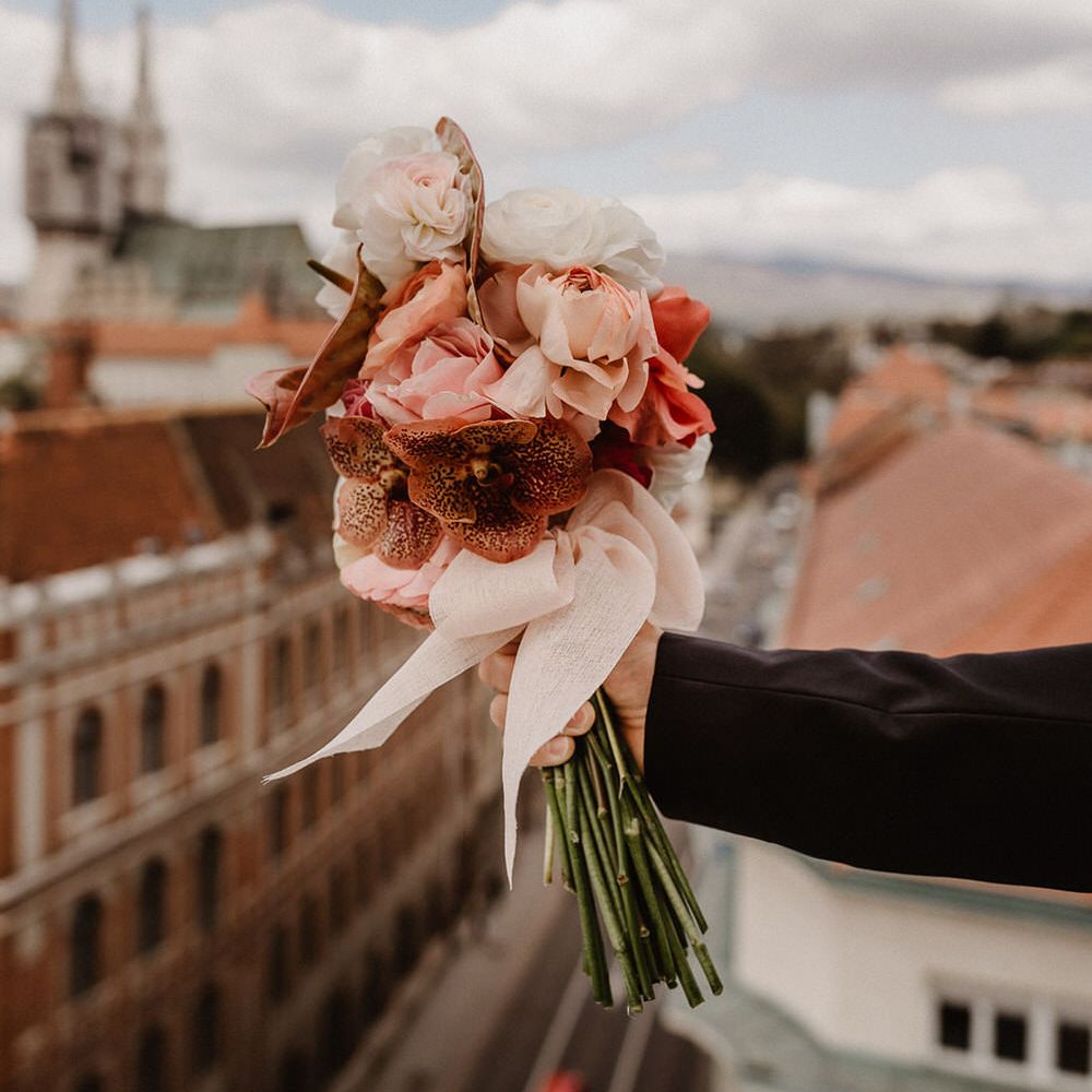 Peach wedding flowers bouquet made of pink, peach and burgundy ranunculi, garden roses and orchids