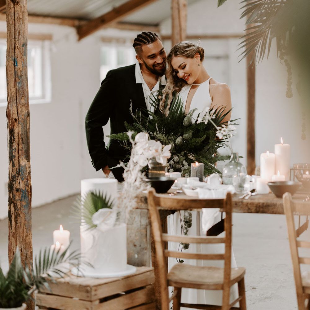 Bride and groom at tropical theme wedding holding a large green bouquet