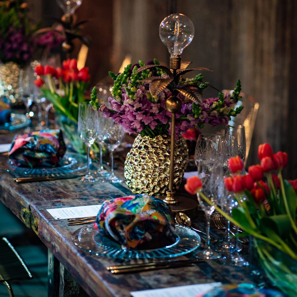 Tropical wedding table decorations with parrots, foliage and Edison bulbs decor 