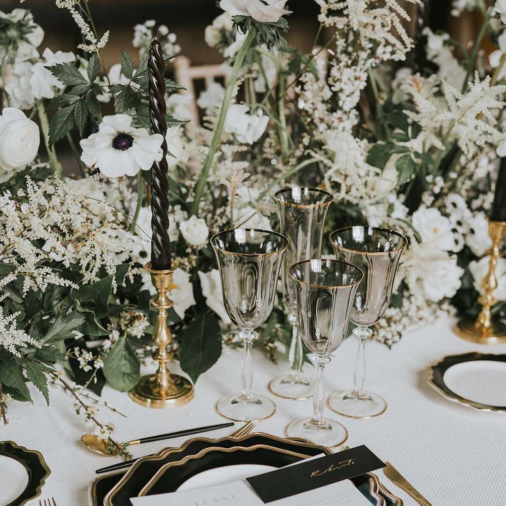 Elegant wedding tableware with black, white and gold plates, gold cutlery and smokey glassware 
